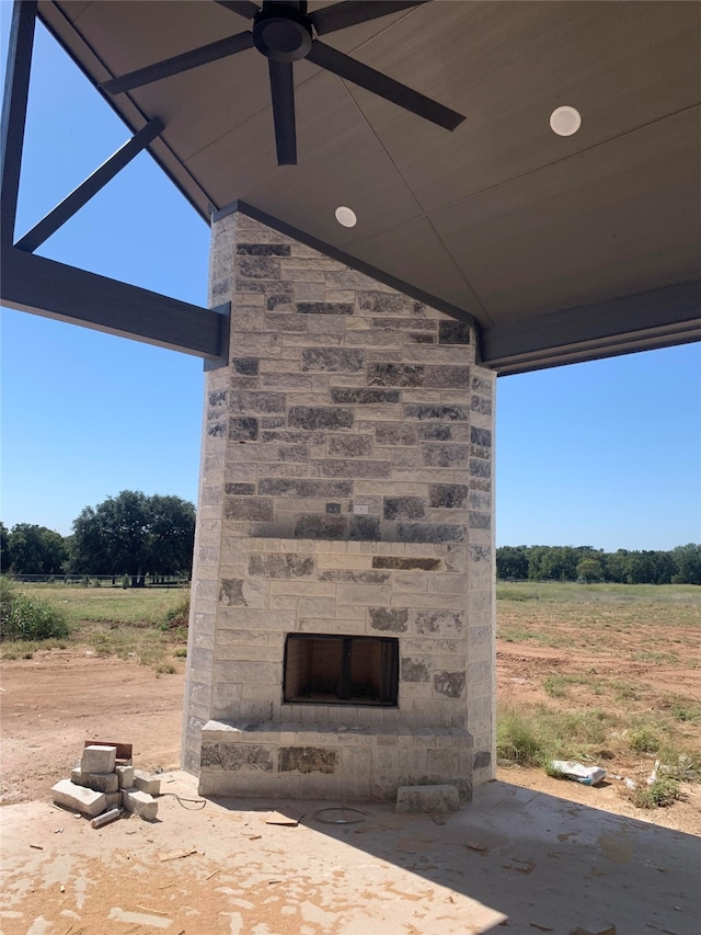 view of patio / terrace featuring ceiling fan, a rural view, and an outdoor stone fireplace