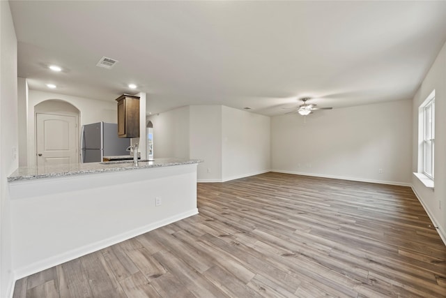 unfurnished living room with ceiling fan, sink, and light hardwood / wood-style floors