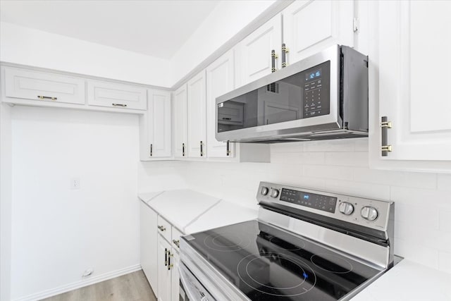 kitchen with white cabinets, appliances with stainless steel finishes, tasteful backsplash, and light hardwood / wood-style flooring