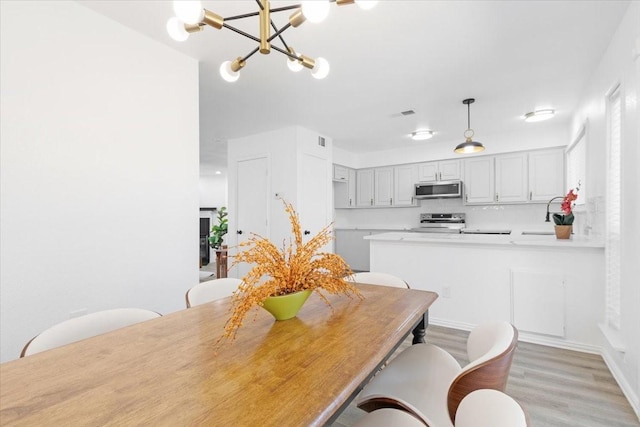 dining room with sink, an inviting chandelier, and light wood-type flooring