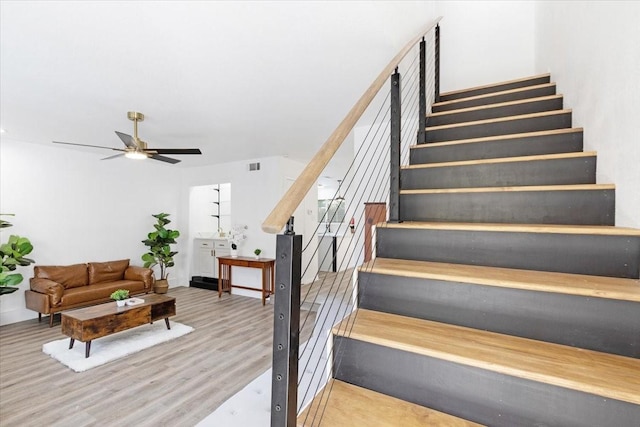 stairs featuring wood-type flooring and ceiling fan