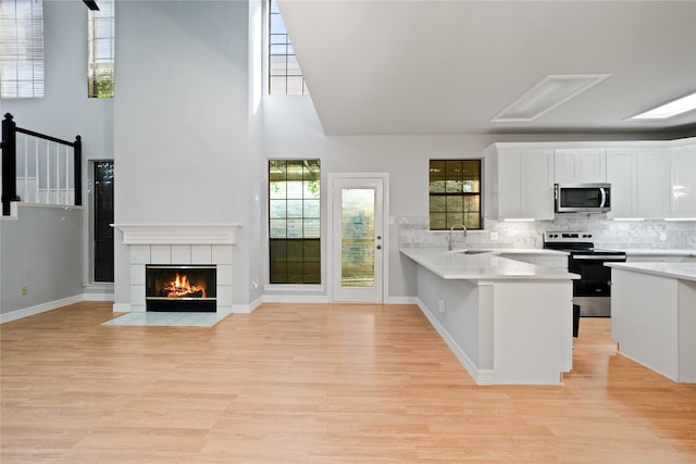 kitchen featuring sink, kitchen peninsula, light hardwood / wood-style flooring, white cabinetry, and stainless steel appliances