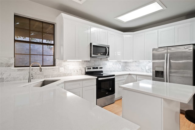 kitchen with appliances with stainless steel finishes, sink, light hardwood / wood-style flooring, and white cabinets