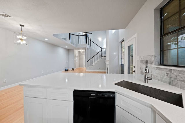 kitchen with pendant lighting, black dishwasher, sink, white cabinets, and an inviting chandelier