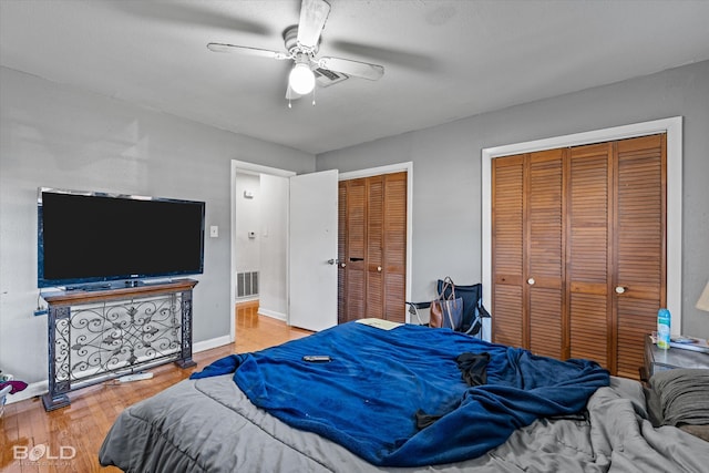 bedroom with hardwood / wood-style floors, ceiling fan, and multiple closets