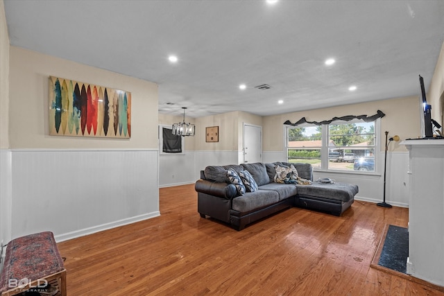 living room featuring wood-type flooring and an inviting chandelier