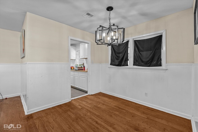 unfurnished dining area featuring hardwood / wood-style floors and a chandelier