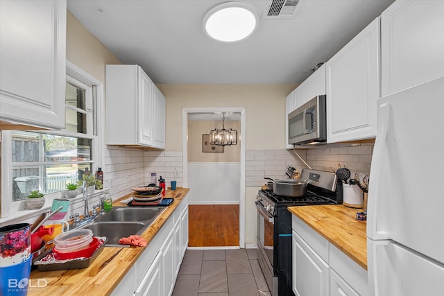 kitchen with wood counters, sink, white cabinets, decorative backsplash, and appliances with stainless steel finishes