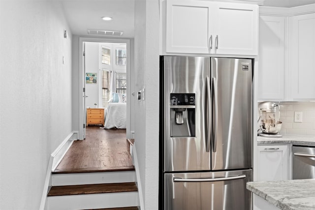 kitchen featuring white cabinets, dark hardwood / wood-style flooring, stainless steel fridge with ice dispenser, and backsplash