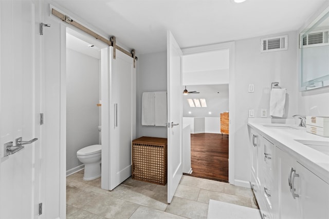 bathroom featuring ceiling fan, toilet, vanity, and hardwood / wood-style flooring