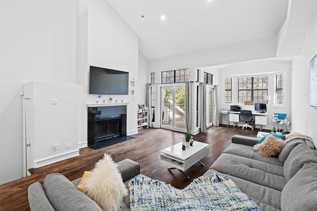 living room featuring dark wood-type flooring, high vaulted ceiling, and a healthy amount of sunlight