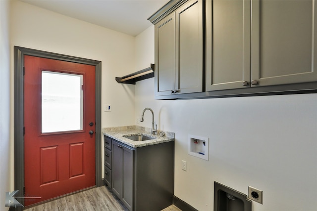 clothes washing area featuring washer hookup, sink, hookup for an electric dryer, light hardwood / wood-style flooring, and cabinets