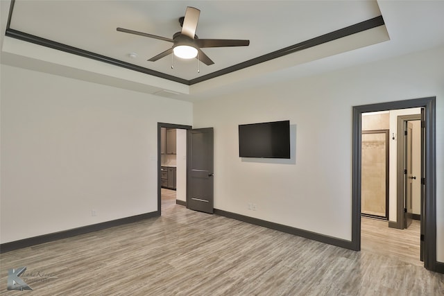 empty room featuring light hardwood / wood-style flooring, a tray ceiling, ceiling fan, and ornamental molding