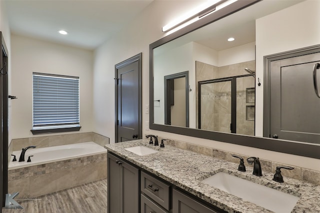 bathroom featuring wood-type flooring, vanity, and plus walk in shower