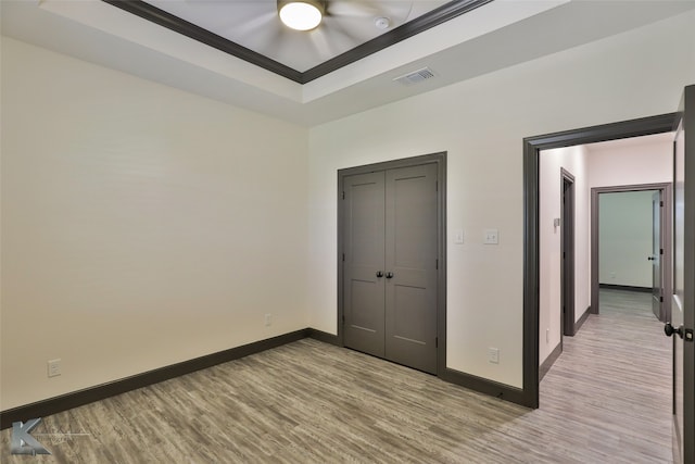 unfurnished bedroom with ornamental molding, a raised ceiling, and light hardwood / wood-style floors