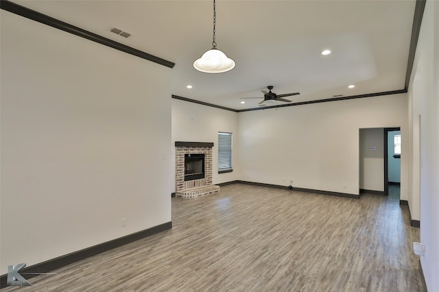 unfurnished living room with ceiling fan, hardwood / wood-style flooring, a fireplace, and crown molding