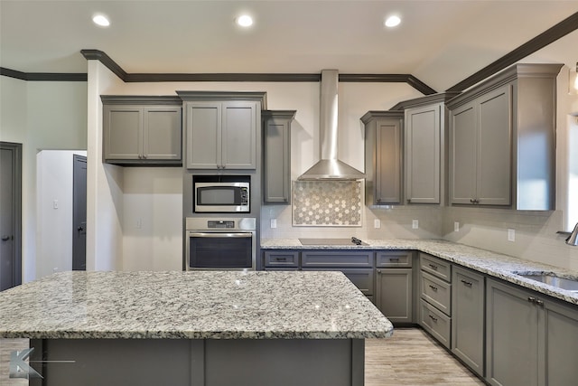 kitchen with appliances with stainless steel finishes, wall chimney exhaust hood, ornamental molding, and sink