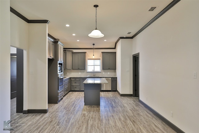 kitchen with appliances with stainless steel finishes, hanging light fixtures, a kitchen island, gray cabinets, and light hardwood / wood-style flooring