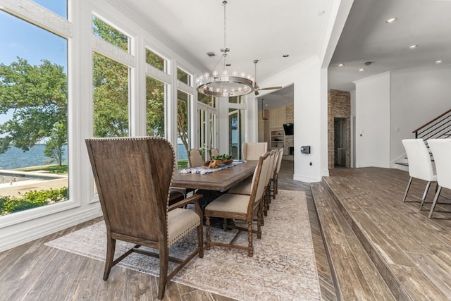 sunroom with ceiling fan with notable chandelier, a water view, and a wealth of natural light