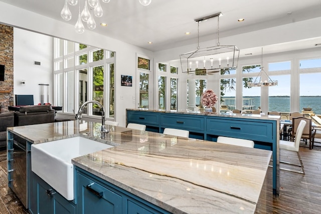 kitchen with a water view, dark hardwood / wood-style flooring, sink, and blue cabinetry