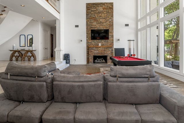 living room featuring plenty of natural light, a high ceiling, and a stone fireplace