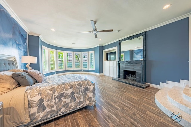 bedroom featuring ceiling fan, a tiled fireplace, dark hardwood / wood-style flooring, and crown molding