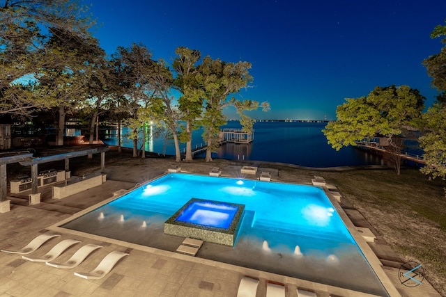 pool at twilight with an in ground hot tub, a water view, and a patio area