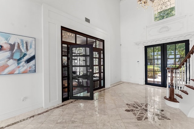 entryway with french doors, a notable chandelier, and a high ceiling