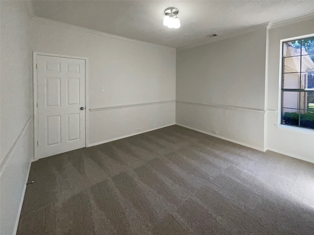 spare room with dark carpet and crown molding