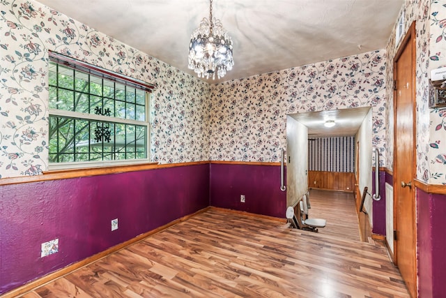 unfurnished room featuring a chandelier and hardwood / wood-style floors