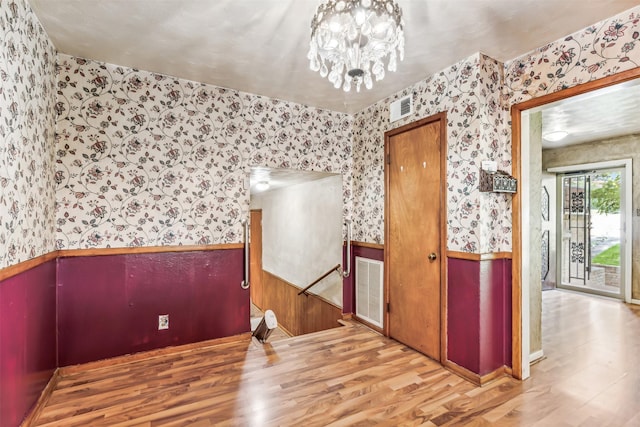 unfurnished room featuring light wood-type flooring and an inviting chandelier