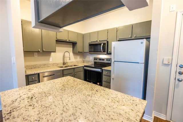 kitchen with appliances with stainless steel finishes, sink, light stone counters, and dark hardwood / wood-style flooring