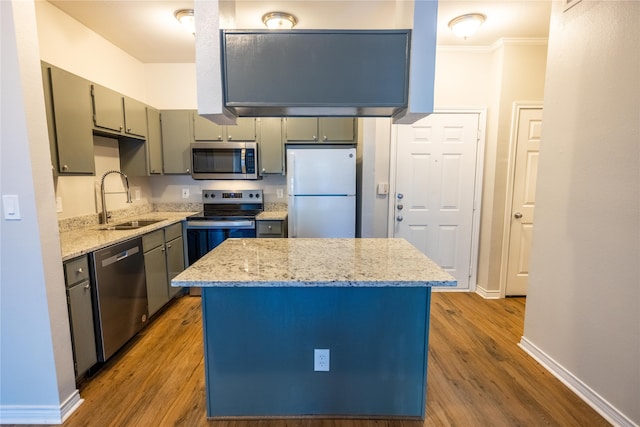 kitchen with light hardwood / wood-style floors, stainless steel appliances, sink, and a kitchen island