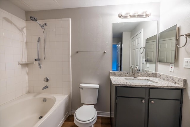 full bathroom featuring hardwood / wood-style flooring, tiled shower / bath combo, vanity, and toilet