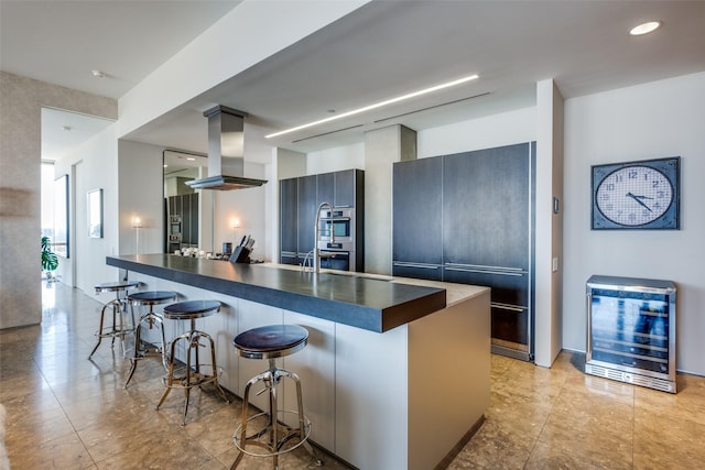 kitchen with a kitchen island, island range hood, a breakfast bar area, wine cooler, and fridge