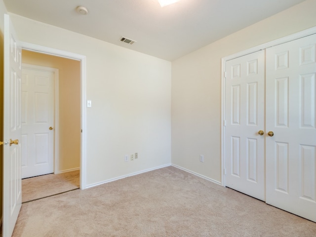 unfurnished bedroom featuring light colored carpet and a closet