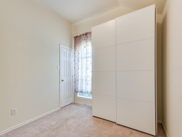 unfurnished bedroom with lofted ceiling and light carpet