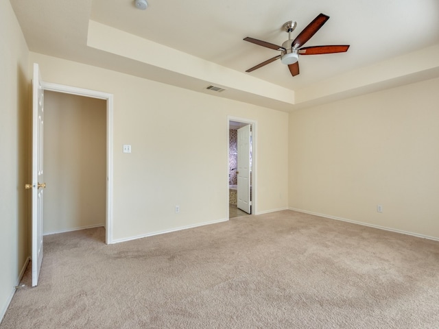 carpeted empty room with a tray ceiling and ceiling fan