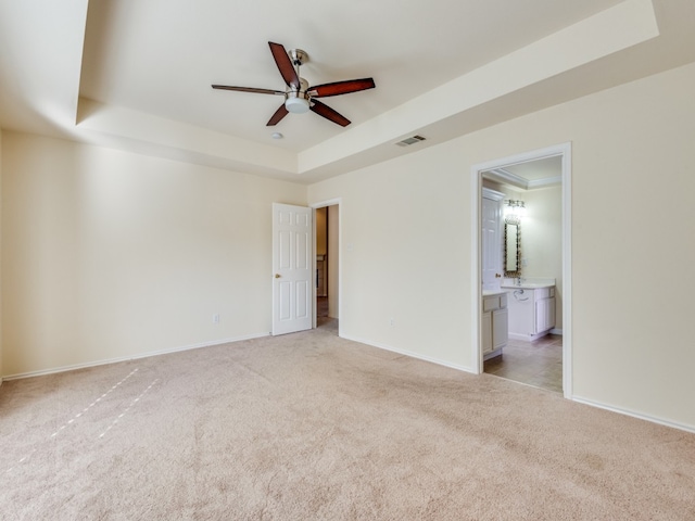 spare room featuring light carpet, ceiling fan, and a raised ceiling