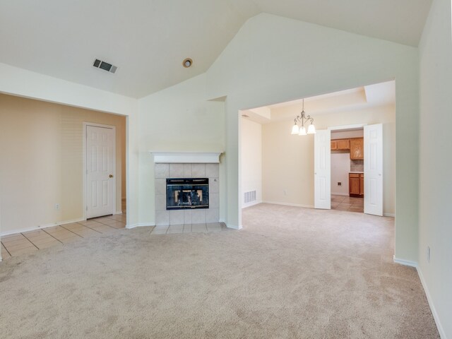 unfurnished living room featuring a fireplace, vaulted ceiling, light carpet, and a notable chandelier