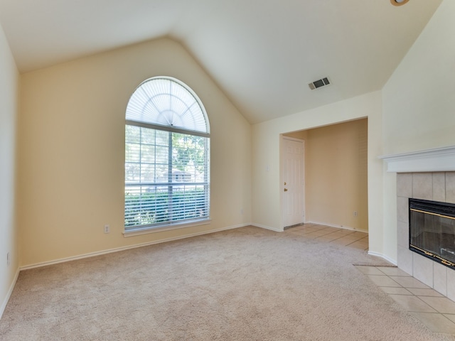 unfurnished living room featuring light carpet, a tiled fireplace, and vaulted ceiling