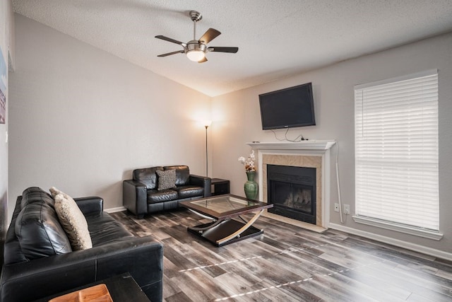 living room with wood-type flooring, a textured ceiling, a fireplace, and ceiling fan