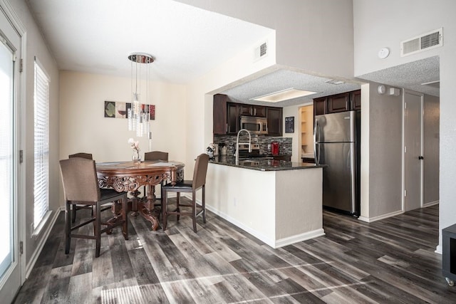 kitchen featuring appliances with stainless steel finishes, a healthy amount of sunlight, dark brown cabinets, and dark hardwood / wood-style floors