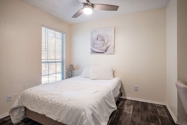 bedroom with ceiling fan, a textured ceiling, and dark hardwood / wood-style flooring