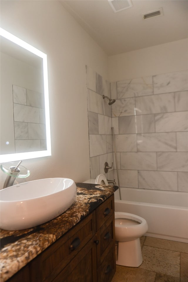 full bathroom with tiled shower / bath, vanity, and toilet