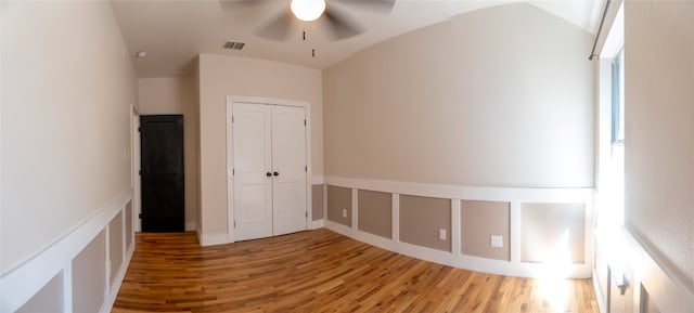 unfurnished bedroom featuring vaulted ceiling, ceiling fan, a closet, and hardwood / wood-style floors