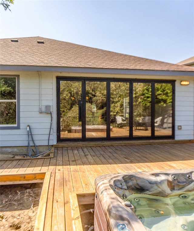 back of house with an outdoor hot tub and a wooden deck