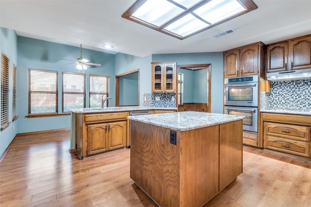 kitchen with sink, light hardwood / wood-style flooring, appliances with stainless steel finishes, tasteful backsplash, and kitchen peninsula