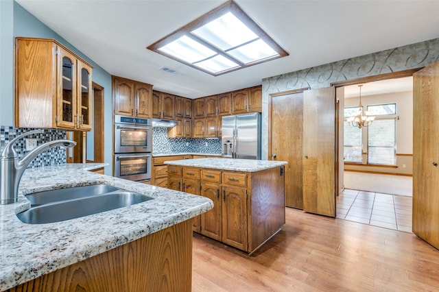 kitchen featuring an inviting chandelier, sink, light wood-type flooring, a kitchen island, and stainless steel appliances