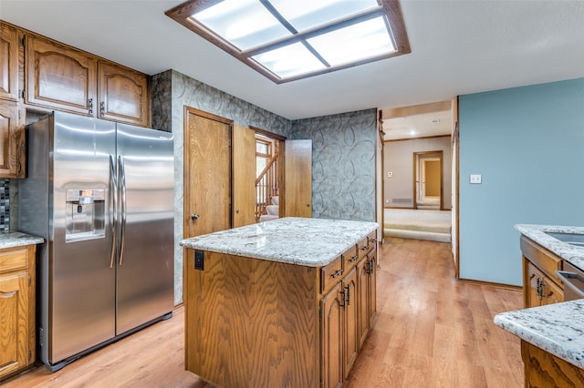 kitchen featuring light stone countertops, stainless steel refrigerator with ice dispenser, a center island, and light hardwood / wood-style floors